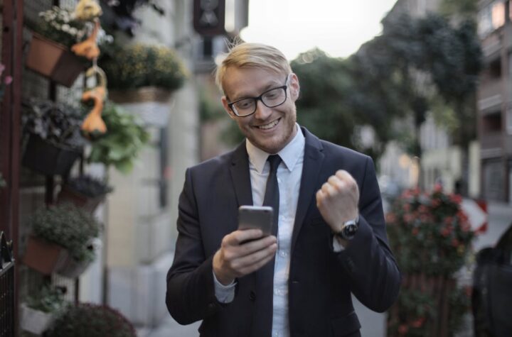 Free Cheerful male manager with mobile phone standing near flower shop in street Stock Photo